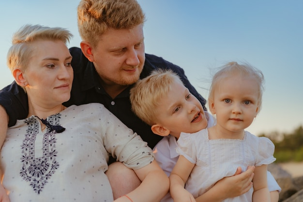 bella famiglia caucasica con mamma in attesa di un bambino si gode il tramonto sulla spiaggia?