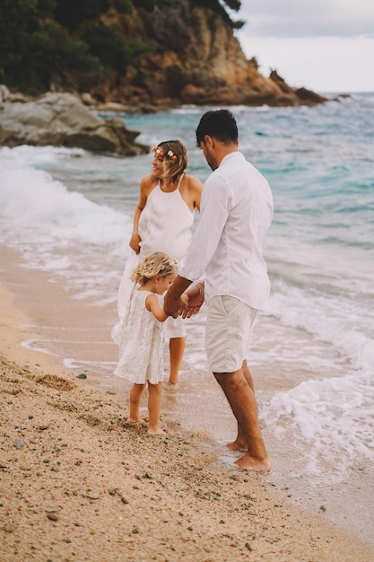 Bella famiglia che cammina lungo una spiaggia mediterranea