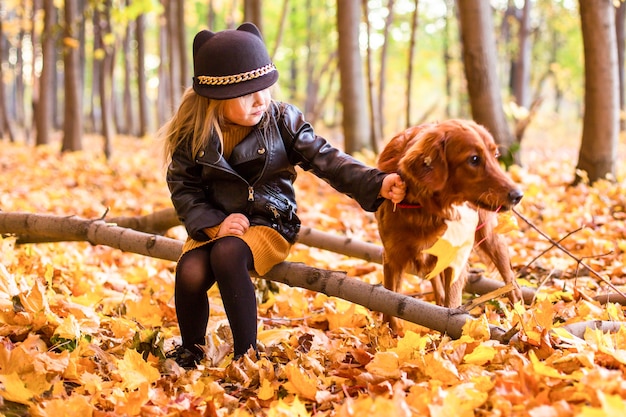 Bella famiglia con un cane golden retriever durante una passeggiata nella natura soleggiata autunnale