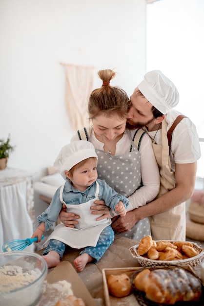 Bella famiglia di mamma, papà e bambino sta preparando la pasta e si abbraccia in cucina