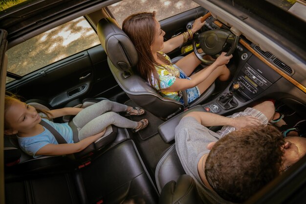 Bella famiglia di tre persone che si diverte a guidare un'auto e fare un viaggio su strada.