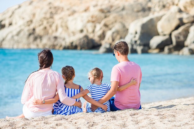 Bella famiglia felice con i bambini che camminano insieme sulla spiaggia tropicale durante le vacanze estive