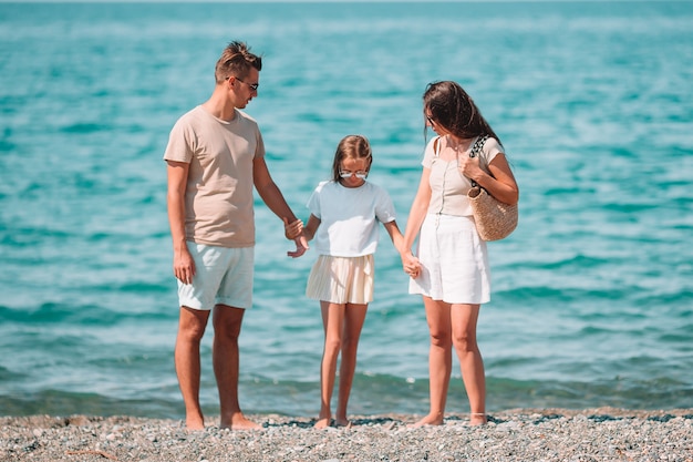 Bella famiglia felice con il bambino insieme sulla spiaggia tropicale durante le vacanze estive