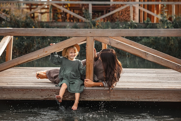 Bella famiglia felice madre e figlia insieme su un molo di legno sulla riva del lago