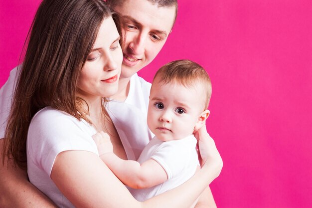 Bella famiglia in posa con il loro bambino in studio con sfondo rosa