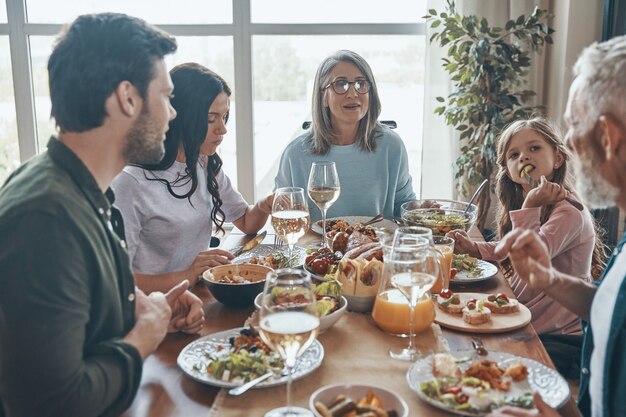 Bella famiglia multigenerazionale che comunica e sorride mentre cena insieme