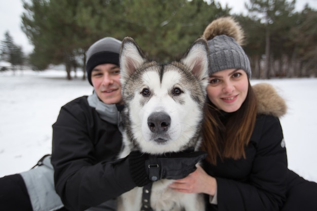 Bella famiglia, un uomo e una ragazza nella foresta invernale con il cane. Gioca con il cane husky siberiano.