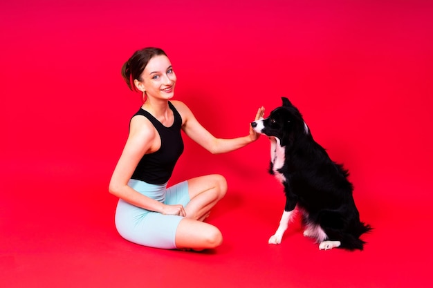 Bella femmina con border collie in studio sullo sfondo giallo e rosso