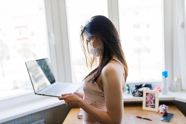 Bella femmina dai capelli scuri in quarantena che indossa la maschera protettiva