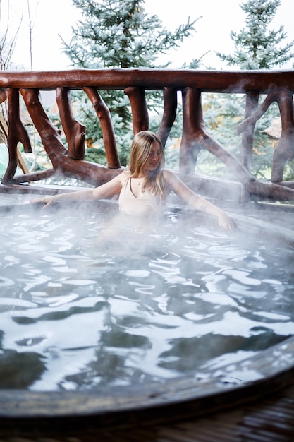 Bella figura donna in costume da bagno. Ragazza in piscina con acqua calda in terrazza, trattamenti spa per il corpo. Jacuzzi all'aperto. Jacuzzi con una ragazza. Relax all'aria aperta, benessere. Cottage con vasca idromassaggio