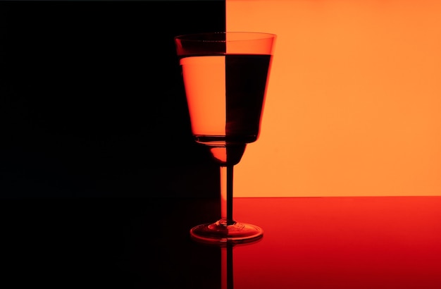 Bella foto di un bicchiere con un drink su uno sfondo nero e rosso con riflessi