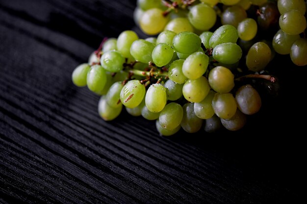 Bella fresca grappolo d'uva su uno sfondo di legno scuro Le goccioline d'acqua Mangiare sano