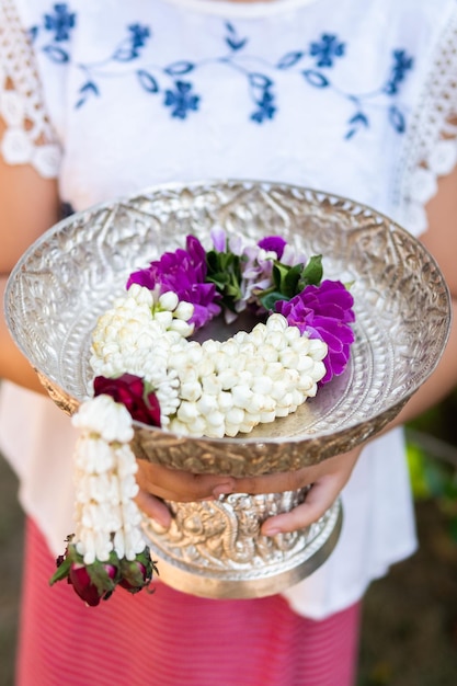 Bella ghirlanda di fiori con fiori freschi in cesto di legno in stile tailandese giallo e verde dalle foglie