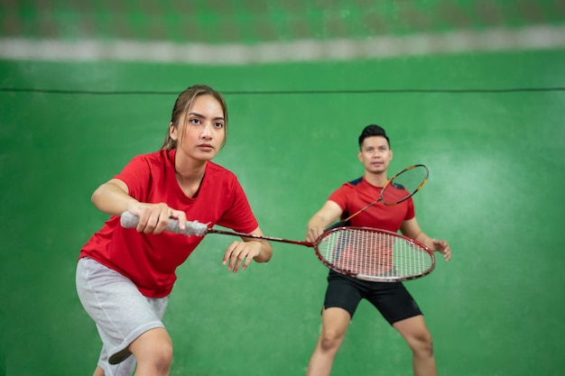 Bella giocatrice di badminton in posizione con il suo partner maschio