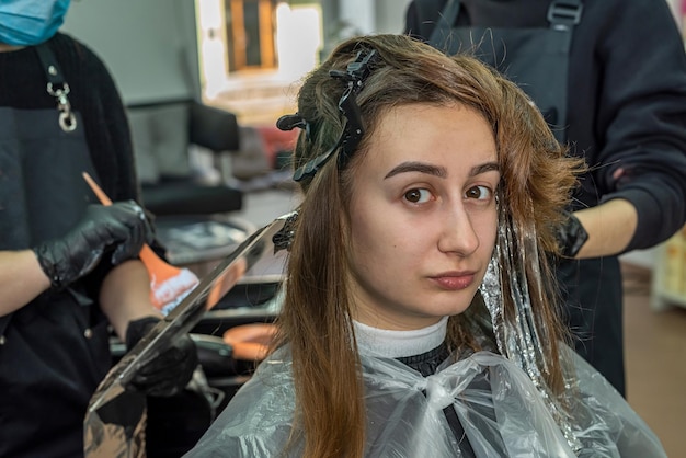 Bella giovane cliente è venuta al salone per tingere i capelli Concetto di colorazione dei capelli Il concetto di procedure con i capelli