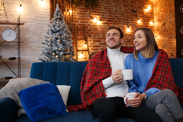 Bella giovane coppia a casa a bere il caffè la mattina di Natale