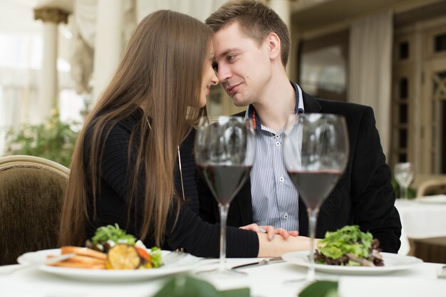 Bella giovane coppia che si bacia al ristorante