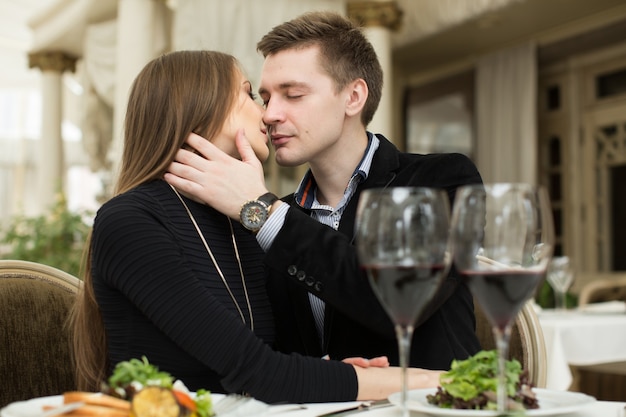 Bella giovane coppia che si bacia al ristorante