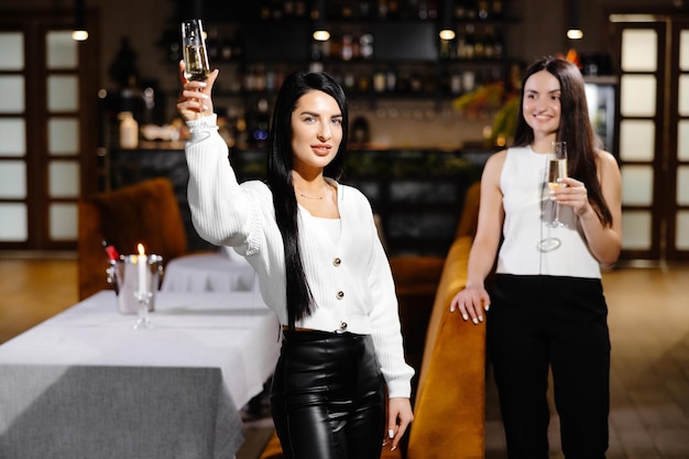 Bella giovane coppia di donne con bicchieri di champagne festeggia nel ristorante di lusso