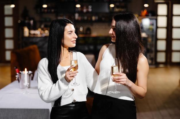 Bella giovane coppia di donne con bicchieri di champagne festeggia nel ristorante di lusso
