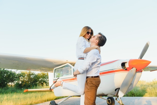 Bella giovane coppia elegante in abiti ufficiali in piedi in aereo privato