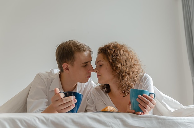 Bella giovane coppia facendo colazione e bevendo caffè a letto