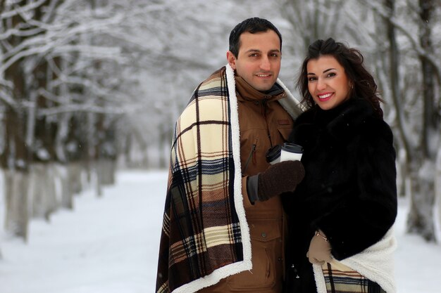 Bella giovane coppia in un parco innevato avvolta in un caldo plaid