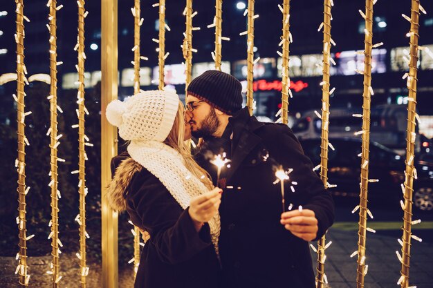 Bella giovane coppia innamorata che si gode la notte di Natale o Capodanno in una strada cittadina.