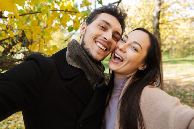 Bella giovane coppia innamorata che trascorre del tempo insieme al parco in autunno, facendo un selfie