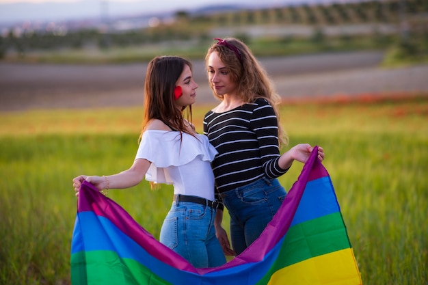 Bella giovane coppia lesbica con la bandiera arcobaleno, uguali diritti per la comunità LGBT