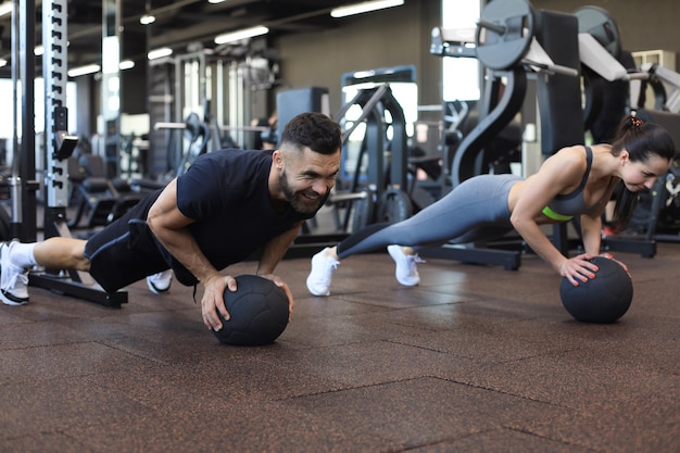 Bella giovane coppia sportiva sta lavorando con la palla medica in palestra.