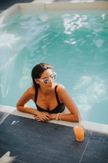 Bella giovane donna a bordo piscina con cocktail