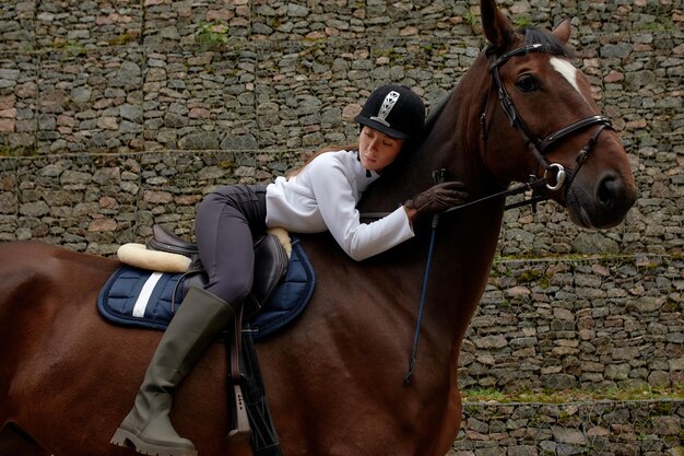 Bella giovane donna a cavallo all'aperto Concetto di cura degli animali Riposo rurale e tempo libero Idea di turismo verde Giovane donna europea che indossa casco e uniforme