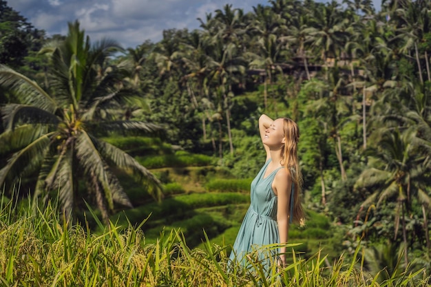 Bella giovane donna a piedi al tipico pendio collinare asiatico con la coltivazione del riso a forma di montagna cascata verde campo di riso terrazze risaie Ubud Bali Indonesia Bali concetto di viaggio