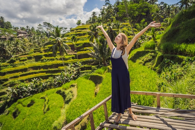 Bella giovane donna a piedi al tipico pendio collinare asiatico con la coltivazione del riso a forma di montagna cascata verde campo di riso terrazze risaie Ubud Bali Indonesia Bali concetto di viaggio