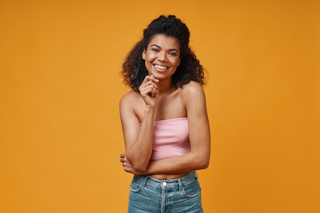 Bella giovane donna africana in abbigliamento casual che guarda l'obbiettivo e sorridente