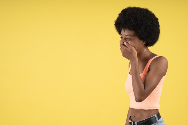 Bella giovane donna afro molto divertente che ride con la mano sulla bocca