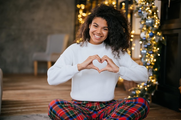 Bella giovane donna afroamericana che fa la forma del cuore con le sue mani