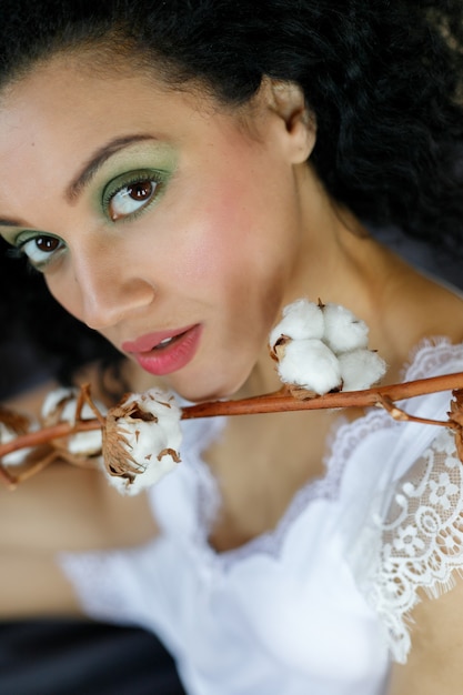 Bella giovane donna afroamericana con ramo di cotone