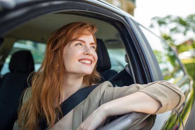 Bella giovane donna alla guida della sua nuova auto al tramonto Donna in auto Ritratto ravvicinato di donna dall'aspetto piacevole con felice espressione positiva donna in abbigliamento casual alla guida di un'auto