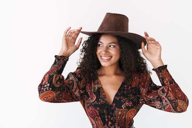 Bella giovane donna allegra che indossa il cappello da cowboy in piedi isolato sul muro bianco