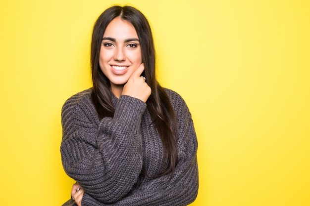 Bella giovane donna allegra in maglione su colore giallo