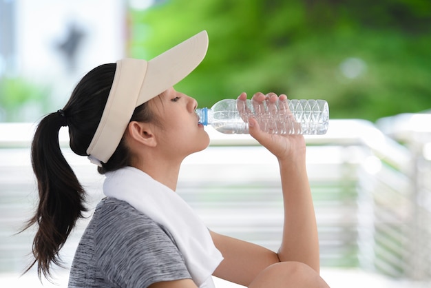 Bella giovane donna Asia acqua potabile dopo l&#39;allenamento.