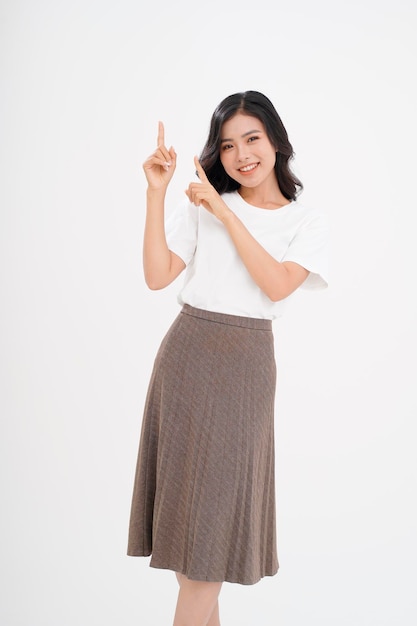 Bella giovane donna asiatica attraente con il gesto della mano che mostra con il dito sullo spazio della copia isolato su priorità bassa