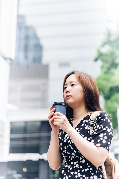 Bella giovane donna asiatica che beve caffè sulla strada della città