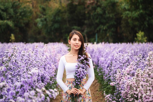 Bella giovane donna asiatica che tiene il fiore di margaret nel giardino