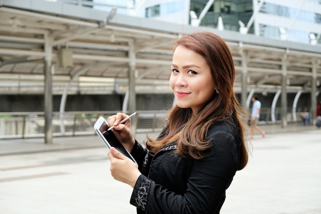 Bella giovane donna asiatica di affari che usando il phon delle cellule.