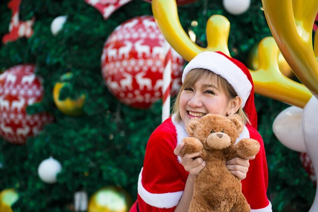 Bella giovane donna asiatica in abiti da Babbo Natale con orsacchiotto bambolaLa gente della Thailandia ha inviato la felicità per i bambiniBuon NataleBenvenuto all'inverno