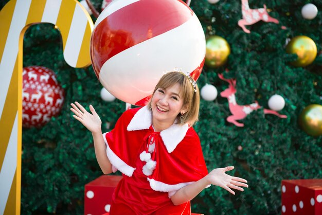 Bella giovane donna asiatica in vestiti di Babbo Natale all'apertoLa gente della Thailandia ha inviato la felicità per i bambiniBuon NataleBenvenuto all'invernoSfondo di Natale decorato