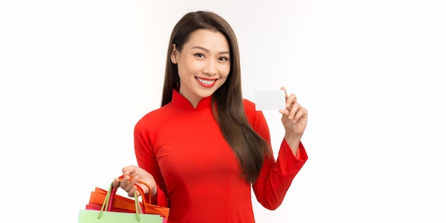 Bella giovane donna asiatica indossare abito vietnamita con carta di credito e borse della spesa su sfondo bianco isolato
